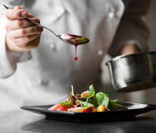 Tasty Indian cuisine from Dhinchak Croydon Chef serving food and drizzling with sauce